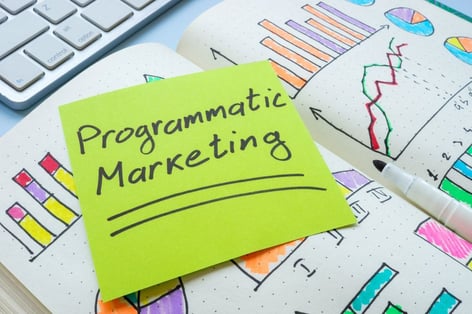 Notebook with programmatic marketing written on a sticky note, illustrating data-driven b2b advertising platforms. 