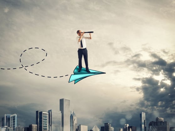Man with a spyglass flying on a blue paper airplane.