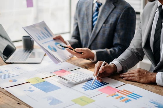 Two professionals analyzing reports and charts during a competitive analysis for business strategy planning.