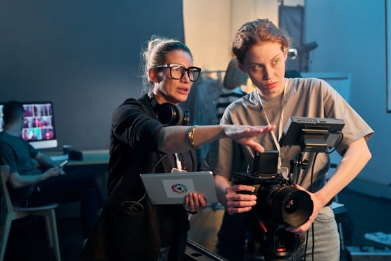 Two women reviewing video content creation on a studio set, part of how to create unique content for digital media.