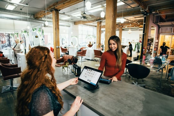 Two women interacting in a salon, representing customer connection and community building on social media.